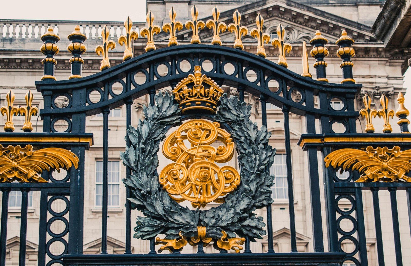 Detailed view of the ornate gold and black iron gate at Buckingham Palace, London.