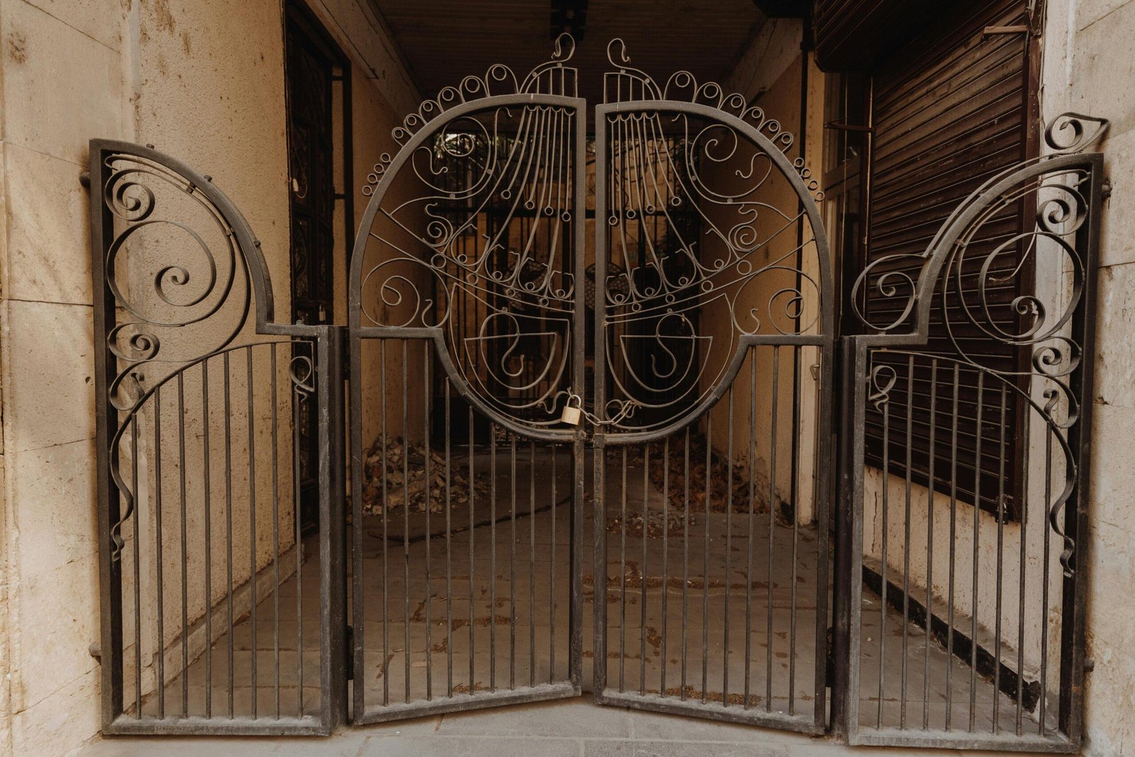 Intricately designed metal gate featuring vintage scrollwork and artistic flourishes, adding charm to an outdoor setting.